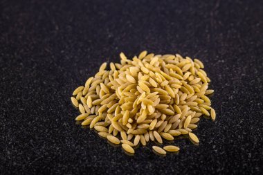 Koyu mermer bir tepside bir yığın orzo makarnasının yakın görüntüsü.