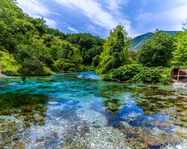 Arnavutluk 'un Muzine kentinde yaz mevsiminde kurulan Mavi Göz pınarından gölün karşısındaki manzara