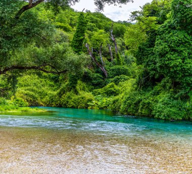 Arnavutluk 'un Muzine kentindeki Muzine kentindeki Mavi Göz pınarından akan geniş nehir boyunca uzanan manzara