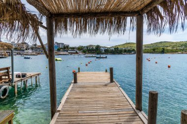 Arnavutluk 'un Ksamil kentindeki ana plajda yaz mevsiminde gölgeli bir iskele manzarası