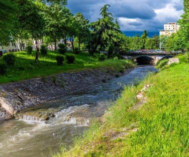 Arnavutluk 'un orta Tiran kentindeki bir köprüye doğru Tiran nehri boyunca uzanan manzara