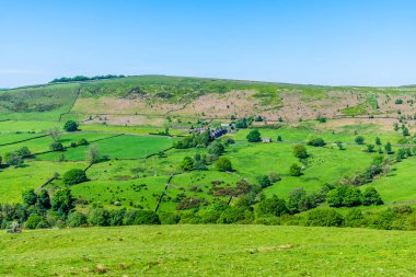 A rural view across the dales towards farmland from the path leading to Luds Church in Staffordshire in summertime clipart