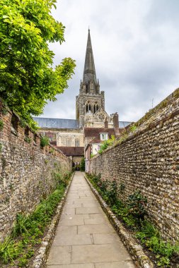 A view up a flower lined path towards the Chichester Cathedral in the center of Chichester, Sussex in summertime clipart