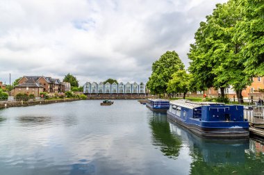 Chichester, Sussex 'te yaz mevsiminde gemi kanalı havzasında demirlemiş eski bir zevk teknesi manzarası.