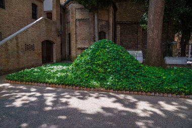 A view towards the hiding place of Dante's remains during World war two in the garden of the Four Arches of Strongarm mausoleum in Ravenna, Italy in summertime clipart