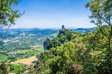 Yaz mevsiminde İtalya 'nın San Marino kentindeki ağaçların arasından üçüncü kuleye doğru bir manzara