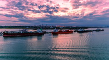 A view from Southampton water towards tankers and the Oil Refinery at Fawley at sunset in Autumn clipart