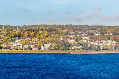 Sonbaharda Saguenay, Quebec, Kanada 'daki körfezdeki yerleşim yerine doğru bir tekne manzarası.
