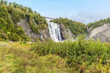 A view past overgrowth beside the regression channel towards the Montmorency falls near Quebec City, Canada in the fall clipart