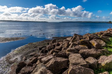 A view over rocks out across the bay on the shoreline at Victoria Park in Charlottetown, Prince Edward Island, Canada in the fall clipart