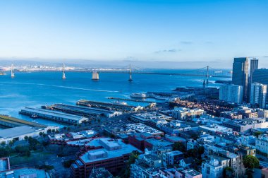 Coit Kulesi 'nden feribot terminallerinin üzerinden akşam vakti San Francisco' daki Oakland Bay Köprüsü 'ne doğru bir manzara.