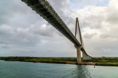İlkbaharda Panama 'daki Panama Kanalı' ndaki tarihi Gatun kilitlerinden ayrıldıktan sonra Atlantik Köprüsü 'nün altından geçecek olan Folks Nehri' nin sağ kıyısına doğru giden bir geminin önü.