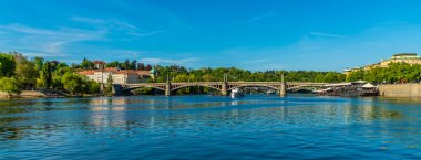 Baharda Vltava nehri boyunca Prag 'daki Manes Köprüsü' ne doğru bir manzara.