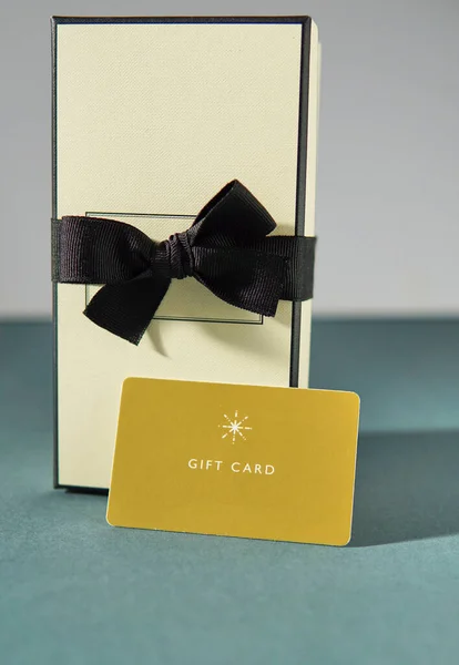 Yellow gift card and a gift box against green background. gift card or gift