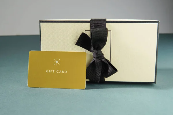 Yellow gift card and a gift box against green background. gift card or gift