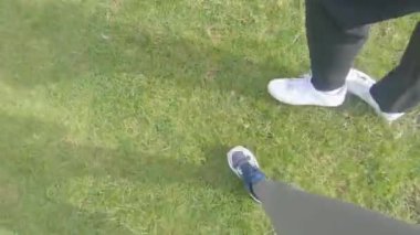 Erkek ve kadın yeşil çimlerde yürüyorlar spor ayakkabılarıyla, ayaklarının manzarası.