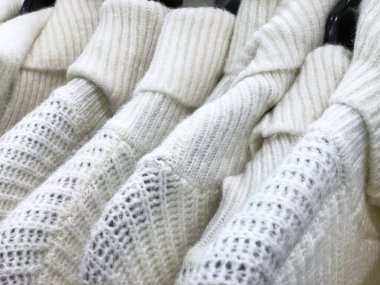 Satılık askılarda asılı açık beyaz renkli kazaklar..