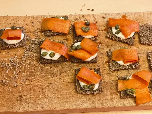 vegan salmon substitute made from carrots on a whole grain baguette slice as healthy veggie snack on a wooden board