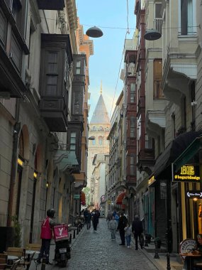 İstanbul, Türkiye - 27 Mayıs 2024: Tarihi mimari ve hareketli yaya faaliyetlerinin yer aldığı Galata Kulesi ile büyüleyici sokak manzarası.