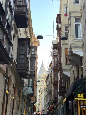 İstanbul, Türkiye - 27 Mayıs 2024: Tarihi mimari ve hareketli yaya faaliyetlerinin yer aldığı Galata Kulesi ile büyüleyici sokak manzarası.