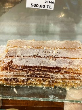 Ekranda taze bir bal peteğinin doğal yapısını ve zenginliğini gösteren yakın plan görüntüsü. Fiyat etiketi görülebilir, değerini gösteriyor. Bu organik bal peteği, sağlıklı ve doğal yiyecekler için ideal saf ve taze bal özünü yakalar.