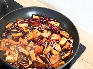 Tofu, lahana, lahana ve sıcak tavada havuçla birlikte renkli vejetaryen kızartması. Canlı sebzeler ve bitki bazlı proteinlerle dolu sağlıklı ve besleyici bir yemek..