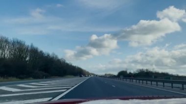 1 Mart 2024 'te Oxford-İngiltere otoyolu açık mavi gökyüzünün altında bulutlu bir şekilde M-40 karayolunda ilerliyor.