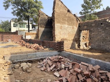 Kısmi duvarlara dağılmış moloz ve tuğlaların yer aldığı bir inşaat sahası, bir bina yıkım sürecini işaret ediyor.