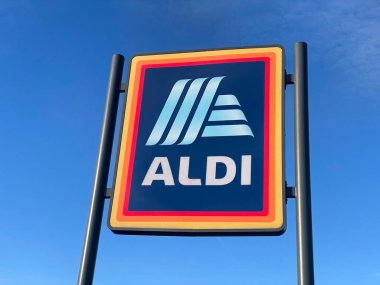 Manchester, İngiltere, 4 Ekim 2024. ALDI mağazasının beyaz bulutlu mavi gökyüzüne karşı ticari işareti. ALDI, iki Alman indirimli süpermarket zincirinin ortak markasıdır..
