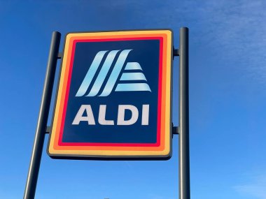 Manchester, İngiltere, 4 Ekim 2024. ALDI mağazasının beyaz bulutlu mavi gökyüzüne karşı ticari işareti. ALDI, iki Alman indirimli süpermarket zincirinin ortak markasıdır..