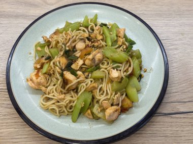 stir-fried noodles combined with tender salmon pieces and fresh green vegetables. Perfectly presented on a light green plate, showcasing a healthy and savory meal. clipart