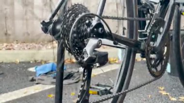 Bir insan sonbahar yapraklarıyla kaplı bir yolda bisiklet tamir ediyor, bisiklet giysisi bakımı. bisiklet bakımı, onarım ve temizlik.