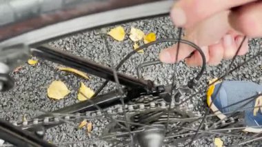 Bir insan sonbahar yapraklarıyla kaplı bir yolda bisiklet tamir ediyor, bisiklet giysisi bakımı. bisiklet bakımı, onarım ve temizlik.