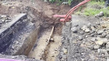Toprak katmanlarını, kırmızı yeraltı kablolarını ve çevresindeki toprak çalışmalarını gösteren bir inşaat alanı. kazı projeleri, veya kamu hizmetleri kurulumları ve onarım.