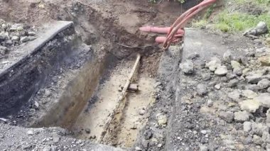 Toprak katmanlarını, kırmızı yeraltı kablolarını ve çevresindeki toprak çalışmalarını gösteren bir inşaat alanı. kazı projeleri, veya kamu hizmetleri kurulumları ve onarım.