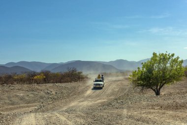KUNENE RIVER, NAMIBIA-DECEMBER 12, 2020: Car on a dusty gravel road along the Kunene River in northern Namibia