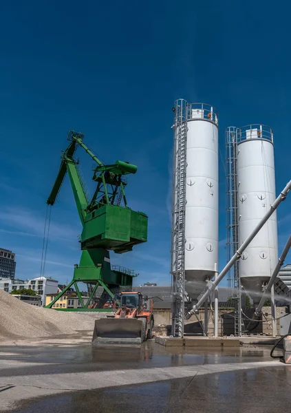 Exterior view of a cement factory with green crane