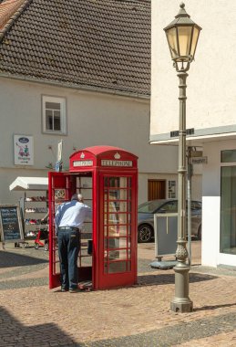HOFHEIM AM TAUNUS, ALMANY-MAYIS 19, 2025: Eski kırmızı bir telefon kulübesinde ücretsiz bir sokak kütüphanesi