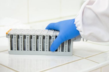 Modern laboratuvarda mavi eldivenle çalışan bir bilim adamı..