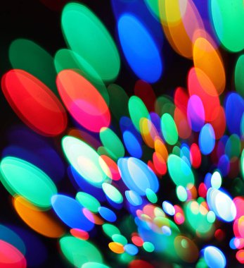 Çok renkli ışıkların şenlikli deseni siyah bir arkaplana çarpıyor.