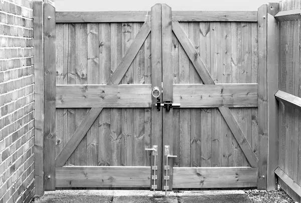 Double wooden gates with lock and drop bolts in black and white