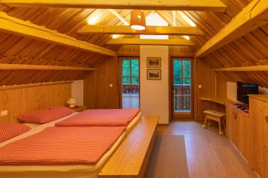 Odanın içi ahşap kabin yatak odası. Büyük pencerenin yanında rahat bir yatak, Bohinj, Slovenya.