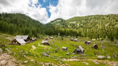 Güzel ahşap kulübeler, Slovenya 'daki Triglav Yedi Göl, Triglav Ulusal Parkı' na giden sakin Julian Alpleri 'nde çam ormanlarının bulunduğu dağın yanında duruyor..