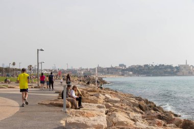 Tel-Aviv halkı gün batımında plajın yanındaki parkta dinleniyor. Jaffa - İsrail: 23 Nisan 2022.
