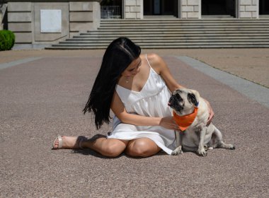 Çekici Asyalı Amerikalı kız pug köpeğiyle üniversite mezuniyetine hazırlanıyor. 