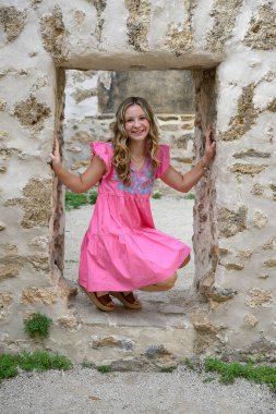 Lise mezuniyet fotoğrafları için tarihi bir ortamda poz veren genç ve güzel bir kız.