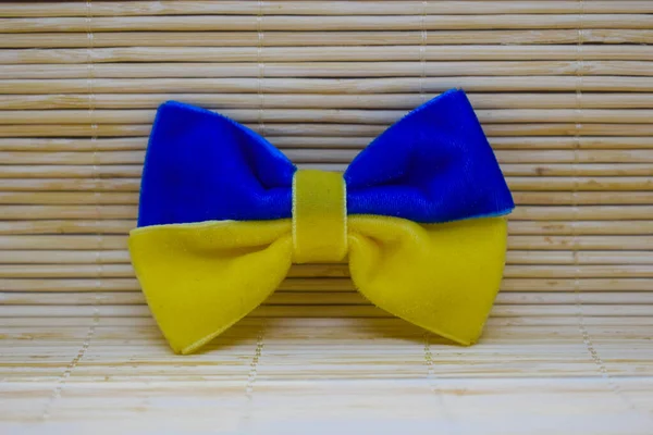 A bow made of blue-yellow fabric as the flag of Ukraine on a bamboo background