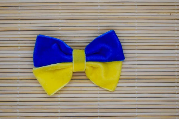 A bow made of blue-yellow fabric as the flag of Ukraine on a bamboo background