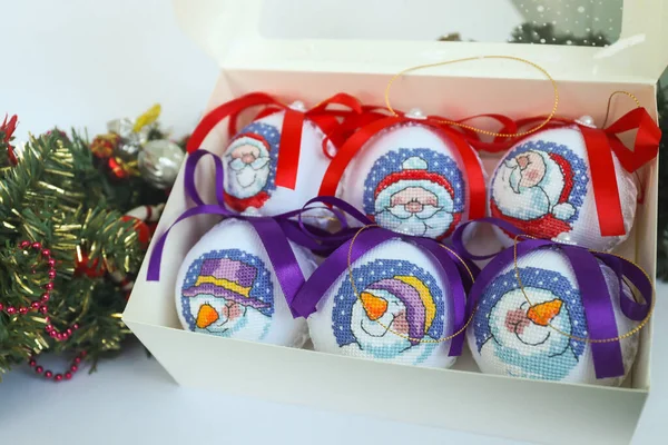 Kardan adam ve Noel Baba ile süslenmiş Noel baloları, bir kutuda haçla işlenmiş.