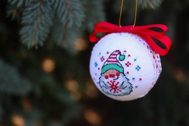 Noel ağacına asılmış haçla işlenmiş bir cüce resmi olan yeni yıl balosu.